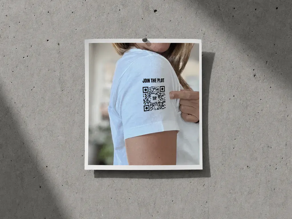 The Invisible Plot_DE 3 QR-Code „Join the Plot“ auf dem Ärmel eines The-Invisible-Plot-Shirts